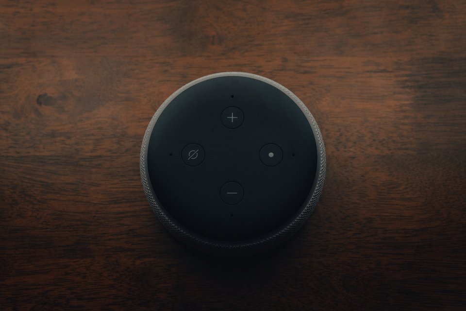 [Translate to English:] A black circular smart device on a wood background
