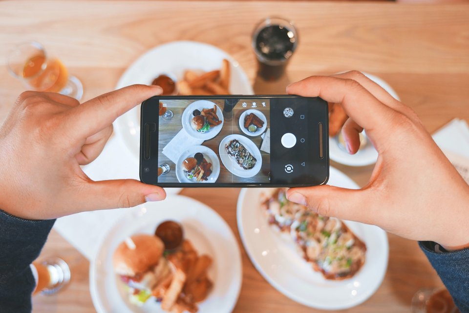 [Translate to English:] Person taking a photo of plates of food with their phone